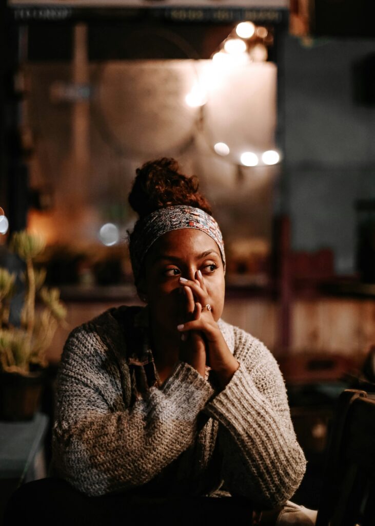 A young woman is sat at a table with her head resting on her hands